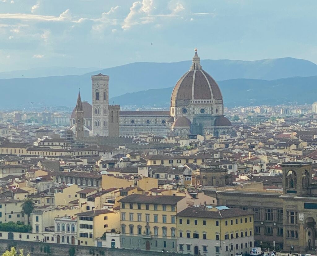 The Florence cityscape during the day. Many yellow and brown buildings with a large domed church in the middle of the frame. 